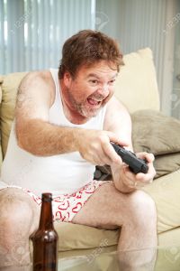 Middle aged man in his underwear playing video games and drinking beer.